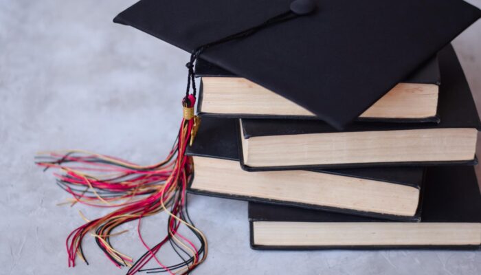 Książki i czapka absolwenta studiów