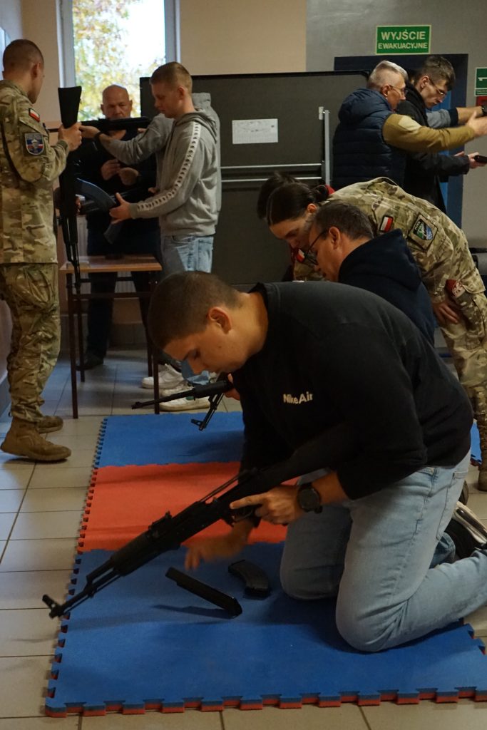 Mężczyzna klęczy, rozkłada broń