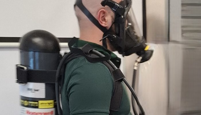 Mężczyzna w aparacie tlenowym na twarzy z butlą na plecach