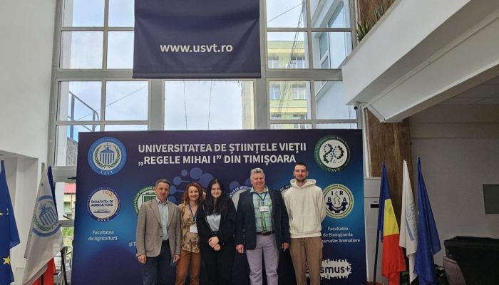 wykładowcy ze studentami na tle ścianki
