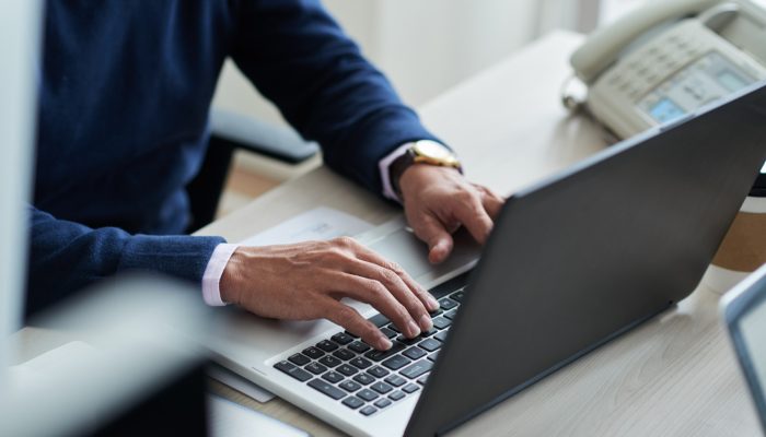 dłonie mężczyzny piszące na klawiaturze laptopa