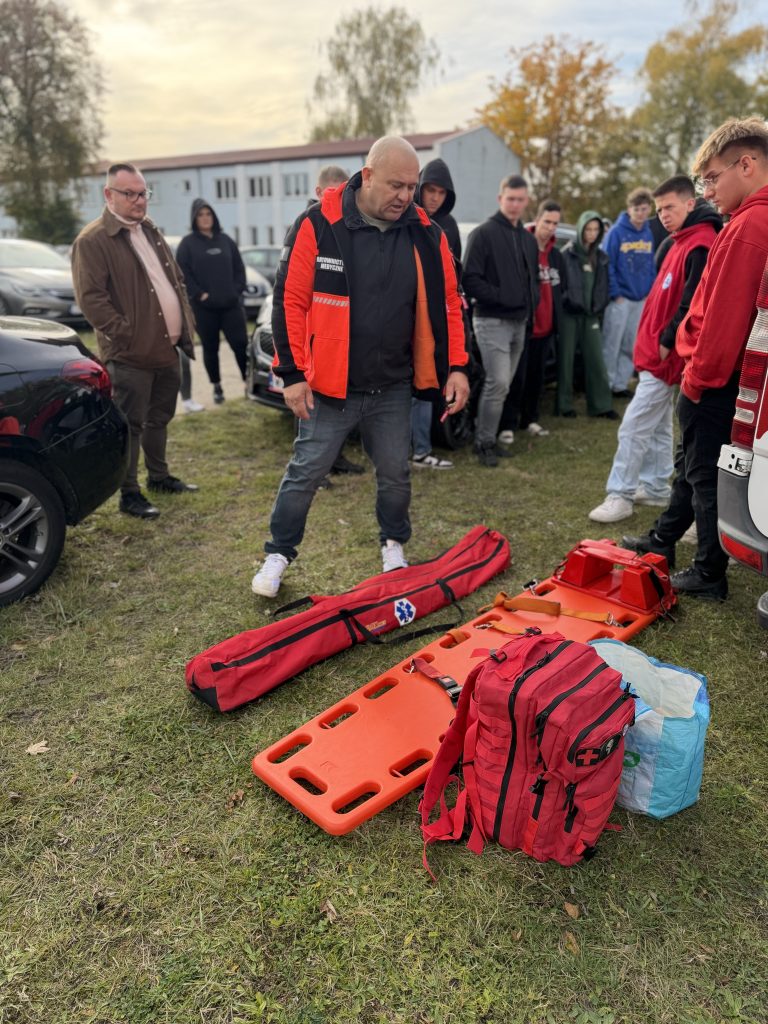 prowadzący stoi na środku, wokół studenci i tłumaczy do czego służy dany sprzęt medyczny
